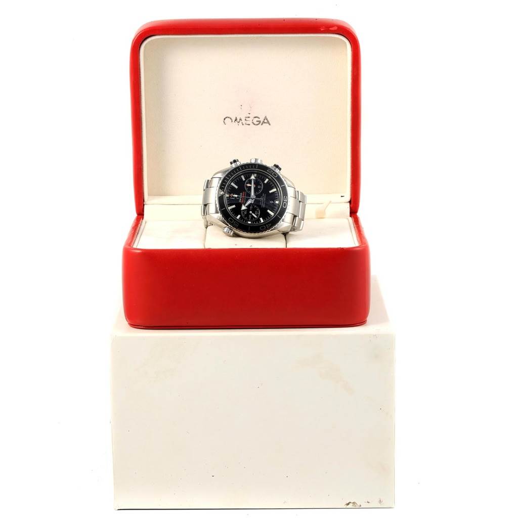 The Omega Planet Ocean 232.30.46.51.01.001 Men's Stainless Steel Black Dial 232.30.46.51.01.001 Men's Stainless Steel Black Dial watch is displayed frontally inside its open red and white case.