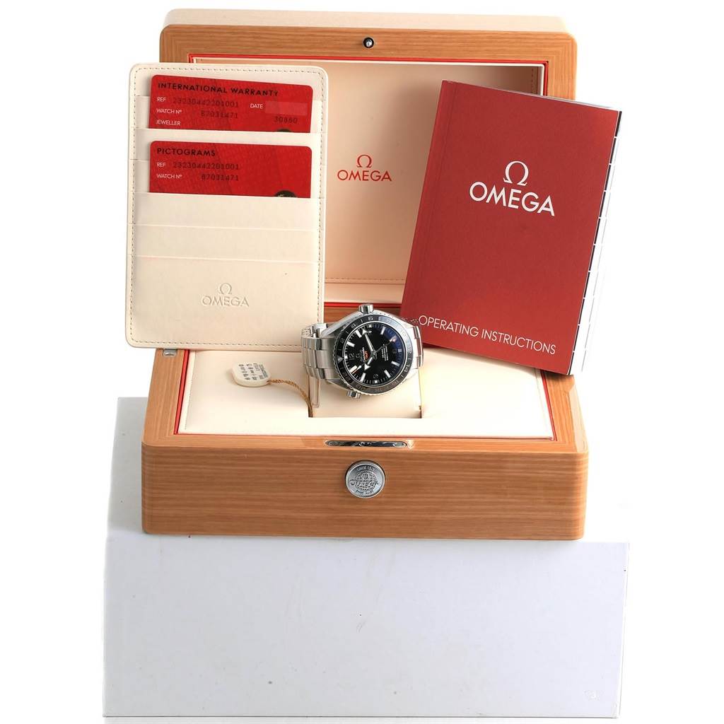 The image shows an Omega Planet Ocean 232.30.44.22.01.001 Men
s Stainless Steel Black Dial 232.30.44.22.01.001 Men
s Stainless Steel Black Dial watch, viewed from the front, along with its box, warranty cards, and operating instructions.