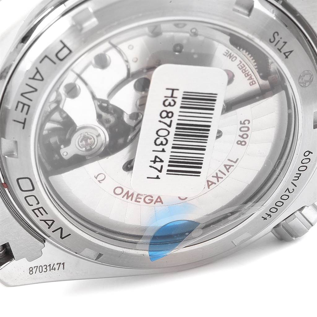 This image shows the back of an Omega Planet Ocean 232.30.44.22.01.001 Men
s Stainless Steel Black Dial 232.30.44.22.01.001 Men
s Stainless Steel Black Dial watch, revealing its movement and a barcode sticker.