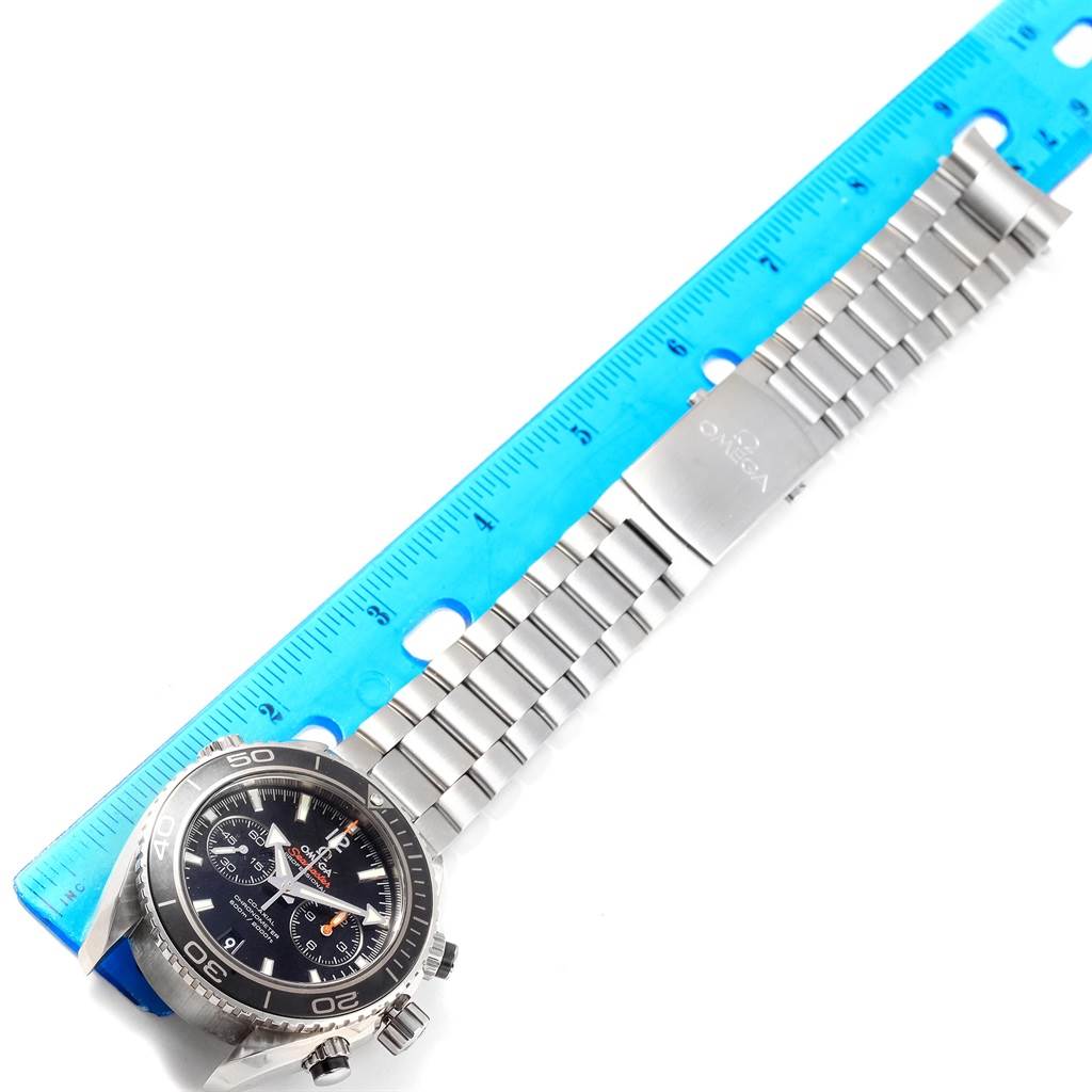 The image shows an Omega Planet Ocean 232.30.46.51.01.001 Men
s Stainless Steel Black Dial 232.30.46.51.01.001 Men
s Stainless Steel Black Dial watch laid flat with its face and metal bracelet aligned next to a ruler.