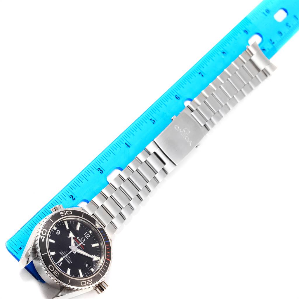 The image shows the Omega Planet Ocean 522.30.46.21.01.001 Men
s Stainless Steel Black Dial 522.30.46.21.01.001 Men
s Stainless Steel Black Dial watch laid flat with a stainless steel bracelet and a blue ruler beside it.