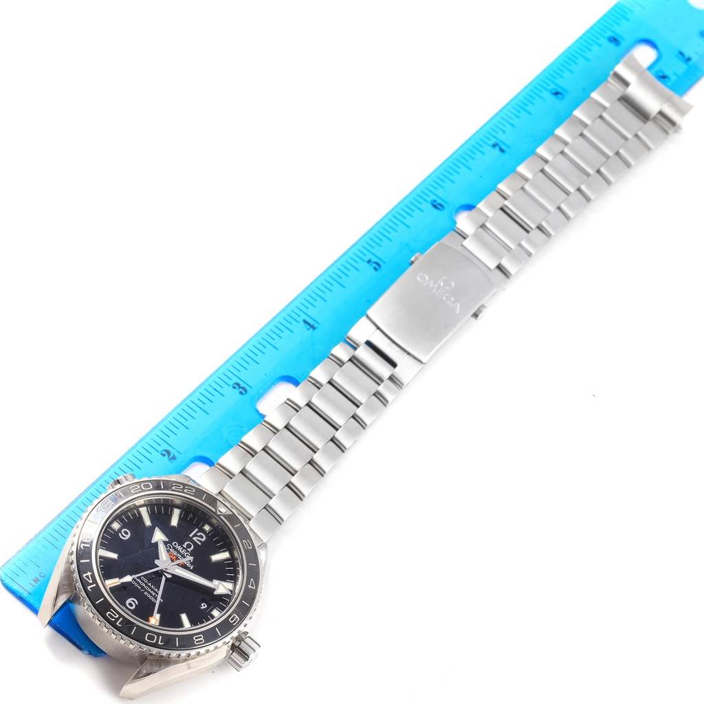 The Omega Planet Ocean 232.30.44.22.01.001 Men's Stainless Steel Black Dial 232.30.44.22.01.001 Men's Stainless Steel Black Dial watch is shown at an angled top view, highlighting the dial, bezel, and metal bracelet with a ruler beside it.