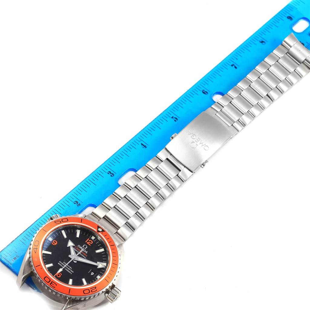 The image shows a top-down view of an Omega Planet Ocean 232.30.46.21.01.002 Men's Stainless Steel Black Dial 232.30.46.21.01.002 Men's Stainless Steel Black Dial watch, including its face, bezel, and metal bracelet, alongside a blue ruler for scale.