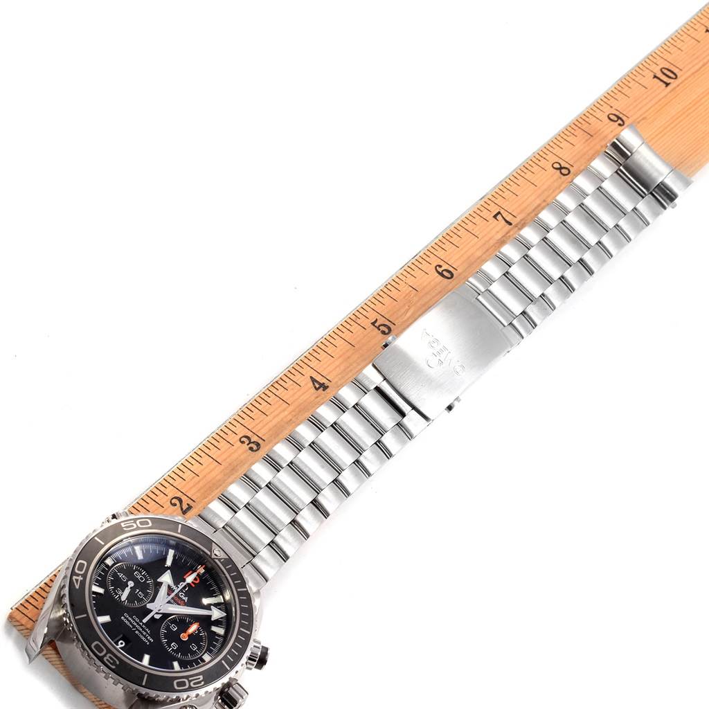 The image shows an Omega Planet Ocean 232.30.46.51.01.003 Men
s Stainless Steel Black Dial 232.30.46.51.01.003 Men
s Stainless Steel Black Dial watch laid out flat next to a ruler, displaying its face, bezel, and metal bracelet.