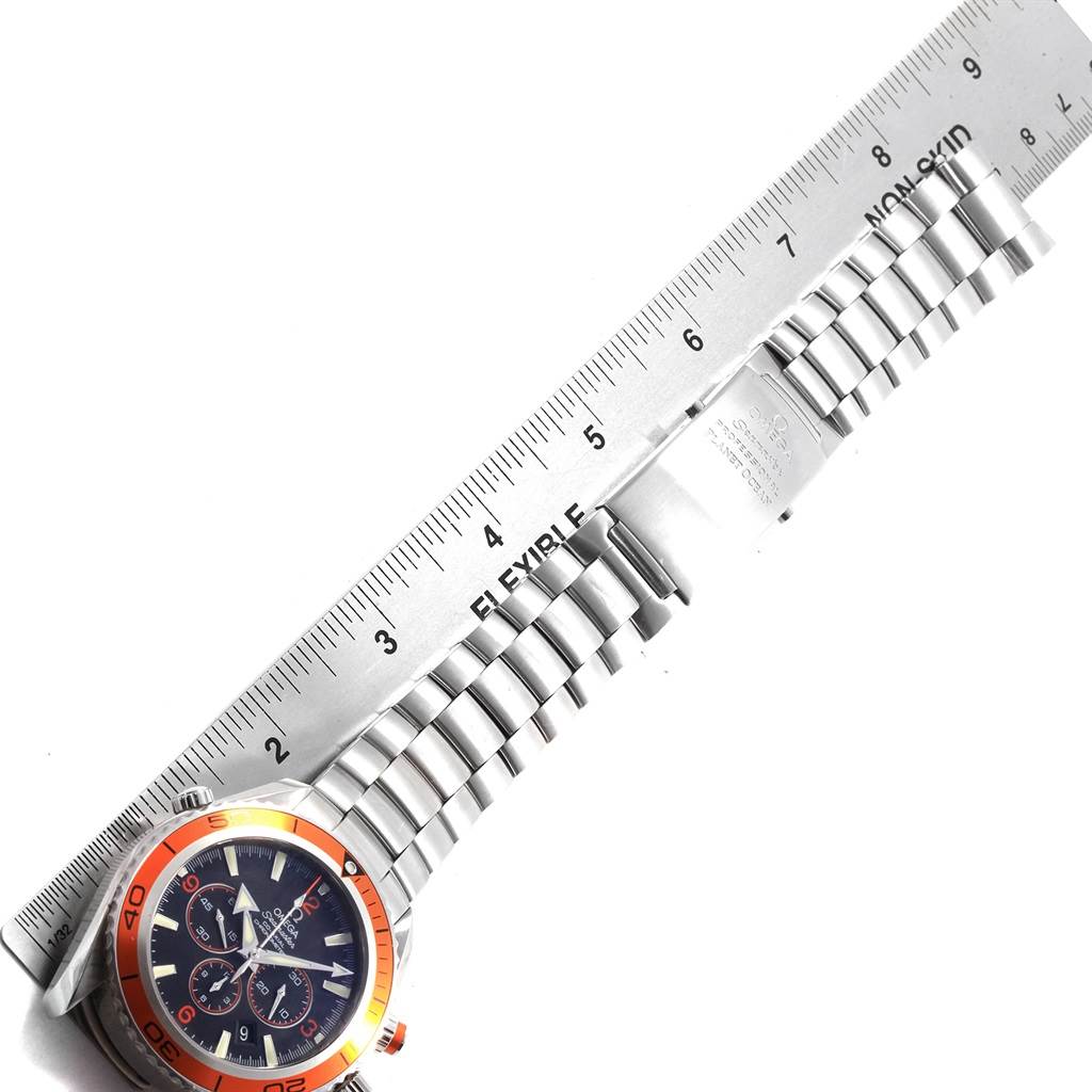 The image shows an Omega Planet Ocean 2218.50.00 Men
s Stainless Steel Black Dial 2218.50.00 Men
s Stainless Steel Black Dial watch laid flat with its stainless steel bracelet and part of its bezel, alongside a metal ruler.