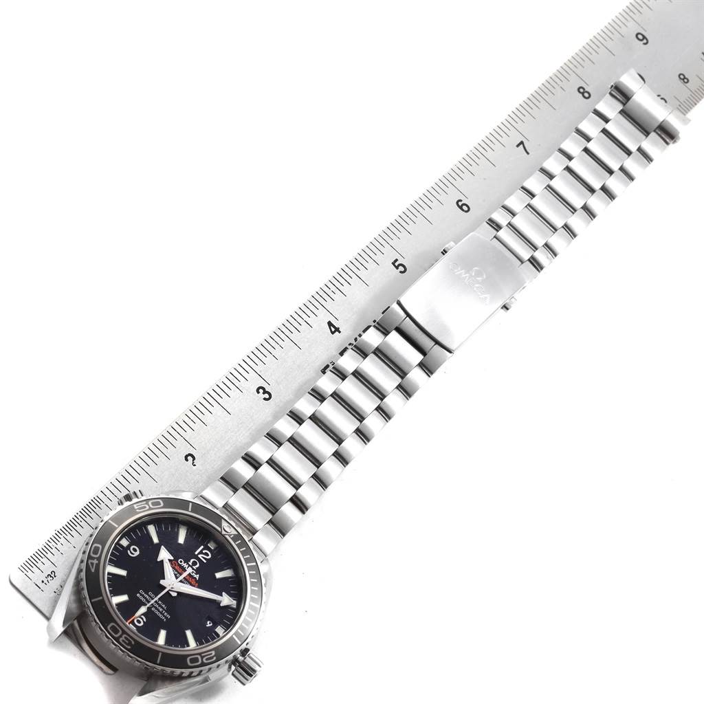 The image shows an Omega Planet Ocean 232.30.42.21.01.001 Men
s Stainless Steel Black Dial 232.30.42.21.01.001 Men
s Stainless Steel Black Dial watch laid flat with its face, stainless steel bracelet, and clasp visible, measured next to a ruler.