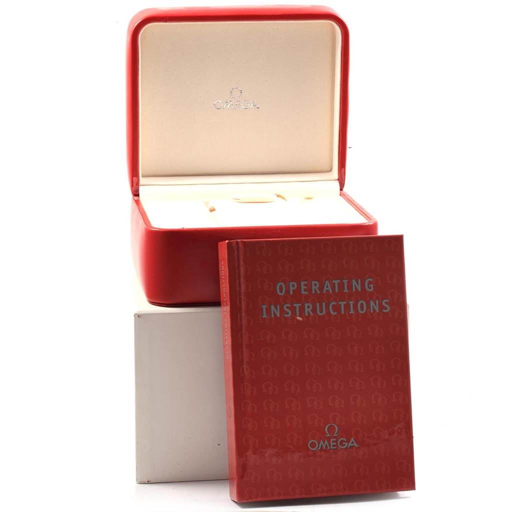 The image shows a red Omega Planet Ocean 215.30.46.51.01.002 Men's Stainless Steel Black Dial 215.30.46.51.01.002 Men's Stainless Steel Black Dial watch case and operating instructions manual placed in front.