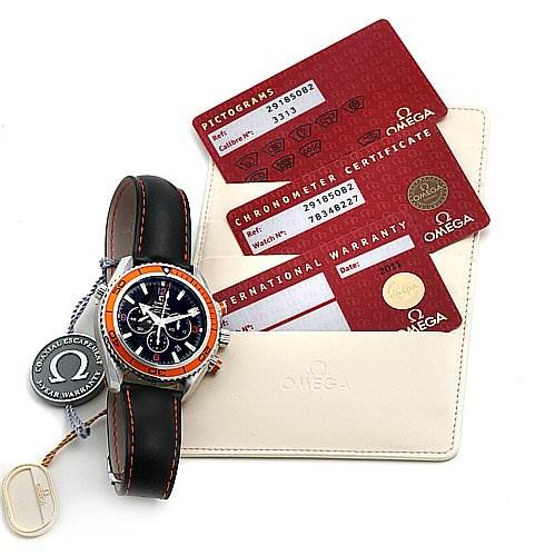 The image shows an Omega Planet Ocean 29185082 OR 2918.   50.   82 Men's Stainless Steel Black Dial 29185082 OR 2918.   50.   82 Men's Stainless Steel Black Dial watch from a top-down angle alongside its warranty cards and a tag.