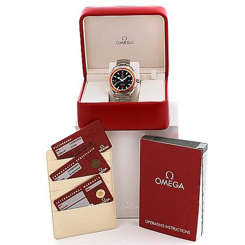 This image shows an Omega Planet Ocean 22085000 Men's Stainless Steel Black Dial 22085000 Men's Stainless Steel Black Dial watch in its case, with operating instructions and certification cards displayed beside it.