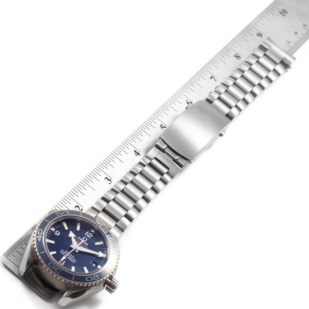 The image shows a horizontal view of the Omega Planet Ocean 232.90.42.21.03.001 Men's Titanium Blue Dial 232.90.42.21.03.001 Men's Titanium Blue Dial watch with its metal bracelet extended next to a ruler.