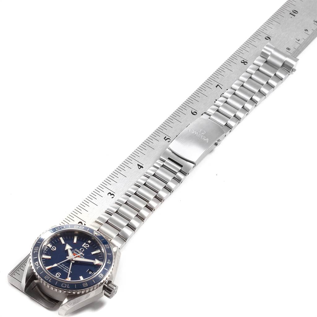 The image shows an Omega Planet Ocean 232.90.44.22.03.001 Men
s Titanium Blue Dial 232.90.44.22.03.001 Men
s Titanium Blue Dial watch laid flat next to a ruler, showcasing its full length and bracelet.