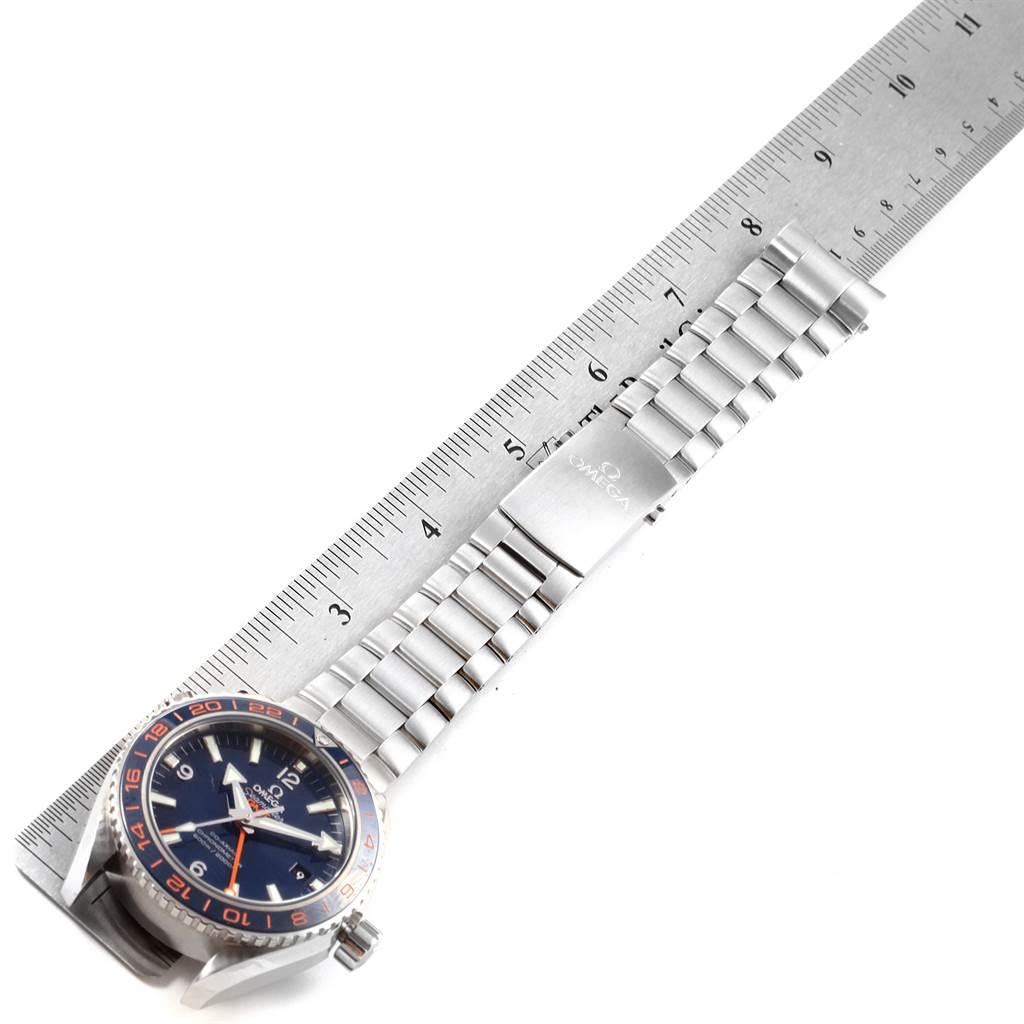 The image shows the Omega Planet Ocean 232.30.44.22.03.001 Men's Stainless Steel Blue Dial 232.30.44.22.03.001 Men's Stainless Steel Blue Dial watch face, crown, and stainless steel bracelet laid out next to a ruler for measurement.