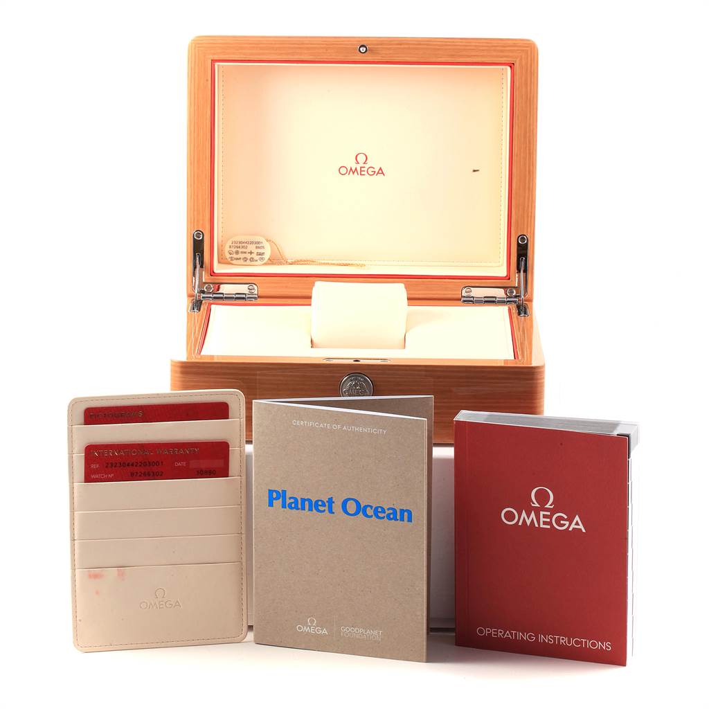 The image shows the box and accessories for the Omega Planet Ocean 232.30.44.22.03.001 Men's Stainless Steel Blue Dial 232.30.44.22.03.001 Men's Stainless Steel Blue Dial watch, including a warranty card, certificate, and operation manual.