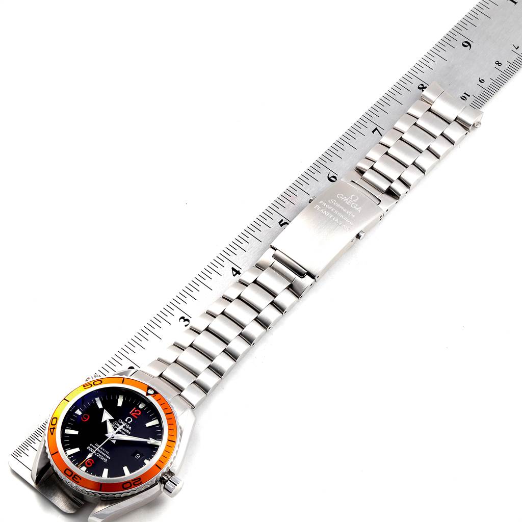 The image shows the front view of the Omega Planet Ocean 2208.50.00 Men
s Stainless Steel Black Dial 2208.50.00 Men
s Stainless Steel Black Dial watch displaying its face, bezel, and metal bracelet laid next to a ruler.