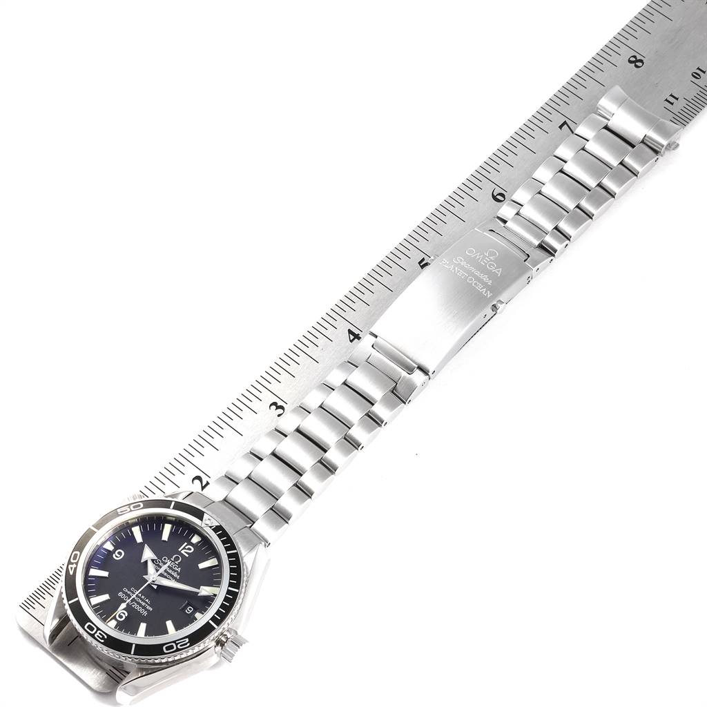 The image shows an Omega Planet Ocean 2201.50.00 Men
s Stainless Steel Black Dial 2201.50.00 Men
s Stainless Steel Black Dial watch laid flat with its dial, bezel, bracelet, and clasp visible against a ruler.