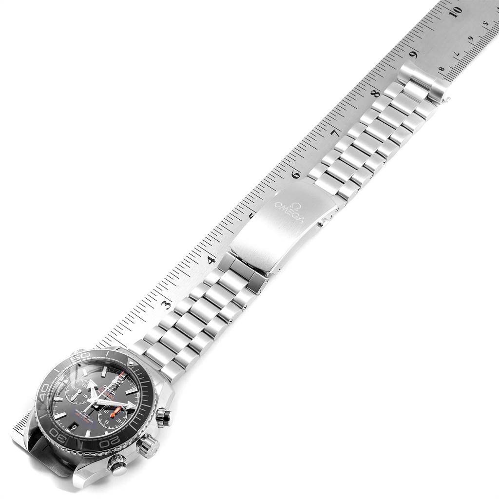 The image shows an Omega Planet Ocean 215.30.46.51.01.001 Men
s Stainless Steel Black Dial 215.30.46.51.01.001 Men
s Stainless Steel Black Dial watch at an angle, highlighting its face, bezel, and metal bracelet along with a ruler.