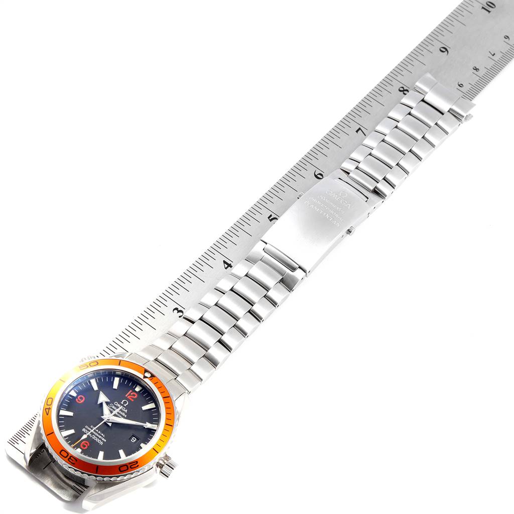 This image shows the Omega Planet Ocean 2208.50.00 Men
s Stainless Steel Black Dial 2208.50.00 Men
s Stainless Steel Black Dial watch laying flat, displaying its face, bezel, bracelet, and clasp alongside a ruler for scale.