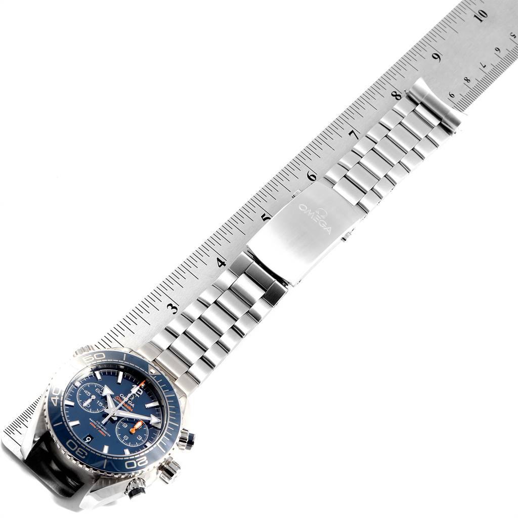 The Omega Planet Ocean 232.90.46.51.03.001 Stainless Steel Blue Dial 232.90.46.51.03.001 Stainless Steel Blue Dial watch is positioned flat, displaying the face, bezel, bracelet, and clasp next to a ruler for scale.