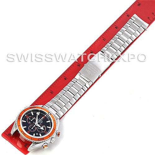 This image shows a top view of an Omega Planet Ocean 2218.50.00 Men
s Stainless Steel Black Dial 2218.50.00 Men
s Stainless Steel Black Dial watch with a stainless steel bracelet laid alongside a red ruler.