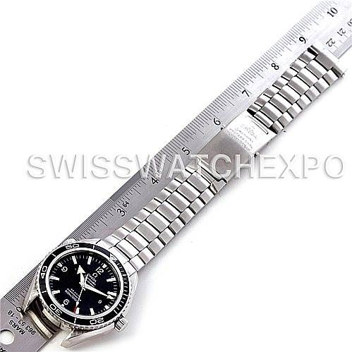 The image shows an Omega Planet Ocean 2200.50.00 Men's Stainless Steel Black Dial 2200.50.00 Men's Stainless Steel Black Dial watch placed next to a ruler, highlighting the watch face, bezel, and metal bracelet band.