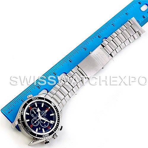 The image shows an Omega Planet Ocean 2210.51.00 Men's Stainless Steel Black Dial 2210.51.00 Men's Stainless Steel Black Dial watch, including the face, bezel, and bracelet, positioned next to a blue ruler for scale.