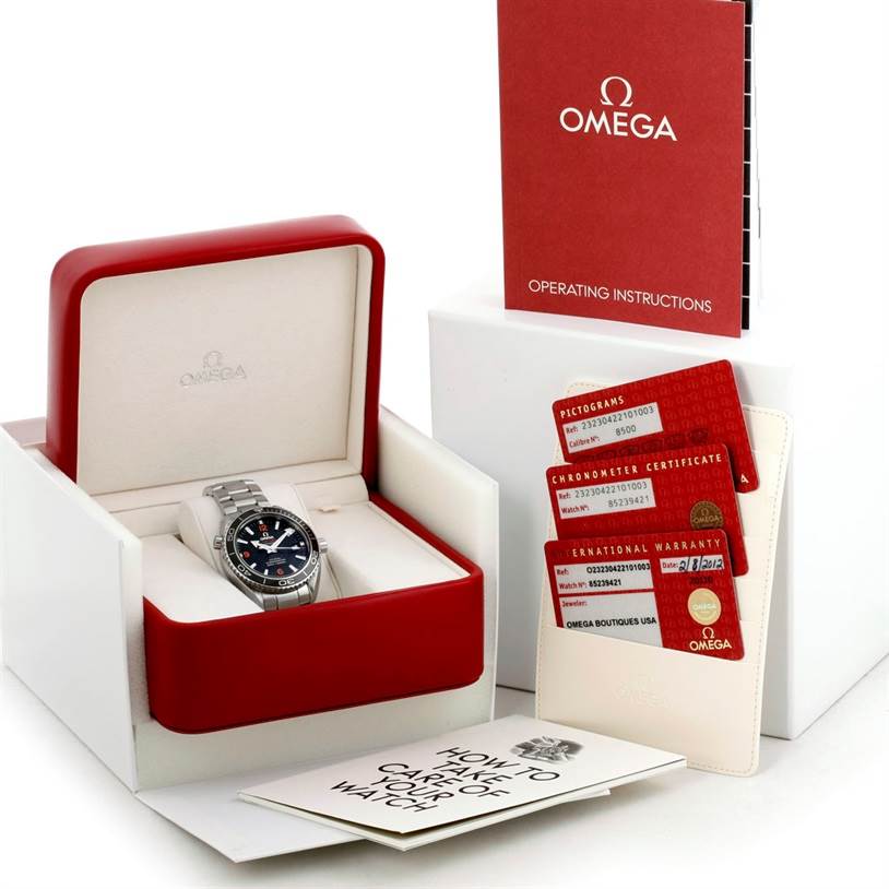 This image shows an Omega Planet Ocean 232.30.42.21.01.003 Men's Stainless Steel Black Dial 232.30.42.21.01.003 Men's Stainless Steel Black Dial watch in its box, with warranty cards, an operating manual, and a care guide displayed alongside.