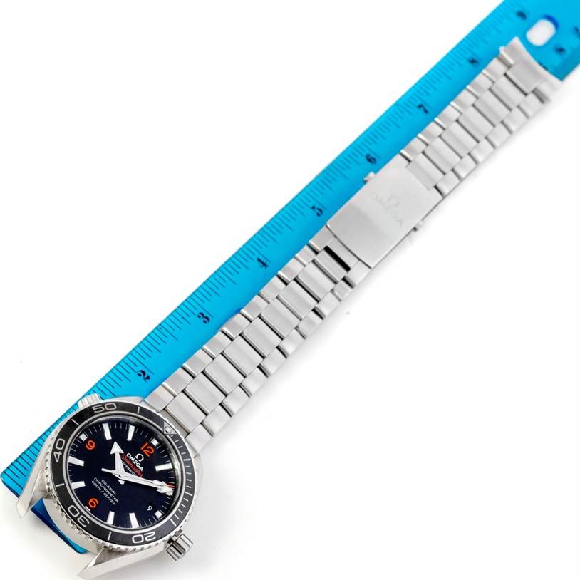 The Omega Planet Ocean 232.30.42.21.01.003 Men's Stainless Steel Black Dial 232.30.42.21.01.003 Men's Stainless Steel Black Dial watch is shown from a top-down angle, displayed with its stainless steel bracelet next to a blue measuring ruler.