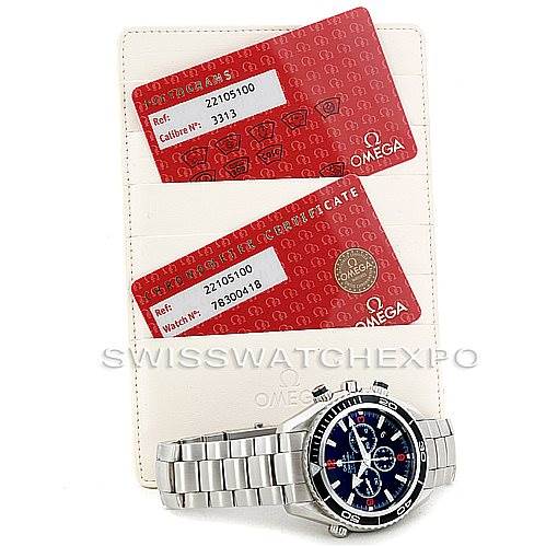 The image shows an Omega Planet Ocean 2210.51.00 Men
s Stainless Steel Black Dial 2210.51.00 Men
s Stainless Steel Black Dial watch along with its red warranty cards, photographed from the top.