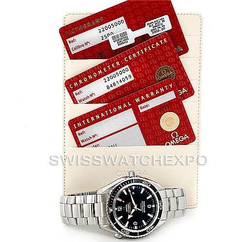 The image shows an Omega Planet Ocean 2200.50.00 Men
s Stainless Steel Black Dial 2200.50.00 Men
s Stainless Steel Black Dial watch with its warranty and chronometer certificates from a top-down angle.