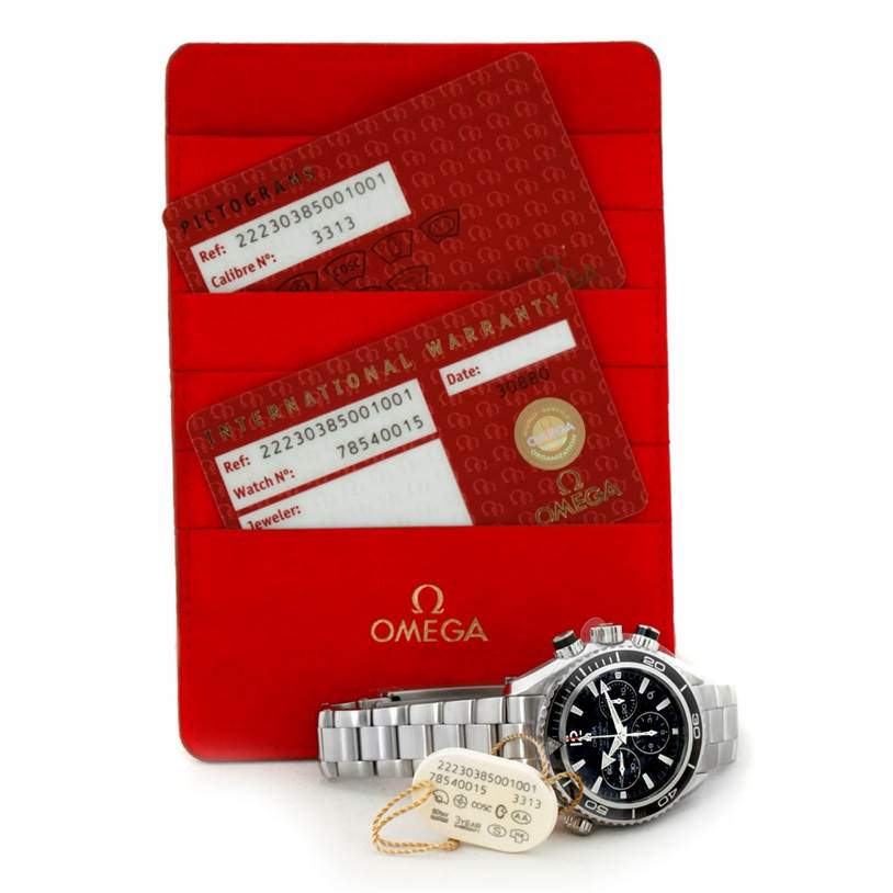 This image shows an Omega Planet Ocean 222.30.38.50.01.001 Stainless Steel Black Dial 222.30.38.50.01.001 Stainless Steel Black Dial watch from an angled top view, revealing its face, metal bracelet, tags, and warranty cards.