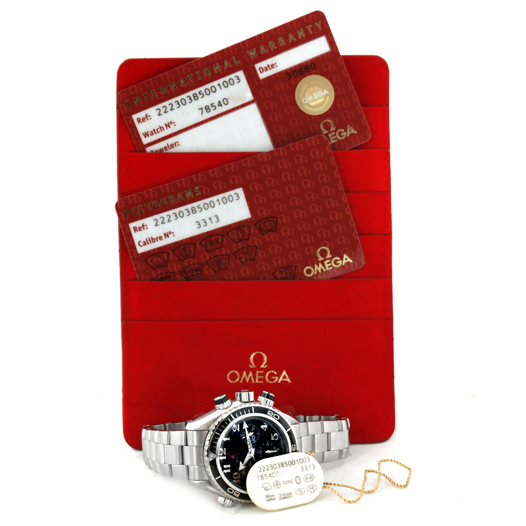 The image shows the Omega Planet Ocean 222.30.38.50.01.003 Men's Stainless Steel Black Dial 222.30.38.50.01.003 Men's Stainless Steel Black Dial watch at a slight angle, along with its warranty cards and tags.