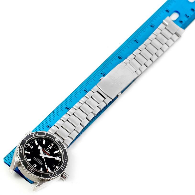 The Omega Planet Ocean 232.30.42.21.01.003 Men
s Stainless Steel Black Dial 232.30.42.21.01.003 Men
s Stainless Steel Black Dial watch is laying flat, showing its stainless steel bracelet and clasp beside a blue ruler for scale.