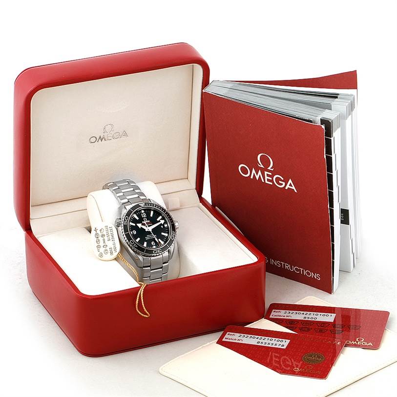 The image shows an Omega Planet Ocean 232.30.42.21.01.003 Men
s Stainless Steel Black Dial 232.30.42.21.01.003 Men
s Stainless Steel Black Dial watch in its open case, accompanied by instruction manuals and identification cards.