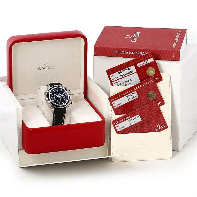 The image shows an Omega Planet Ocean 2910.50.81 Men
s Stainless Steel Black Dial 2910.50.81 Men
s Stainless Steel Black Dial watch in its box with warranty cards and operating instructions.