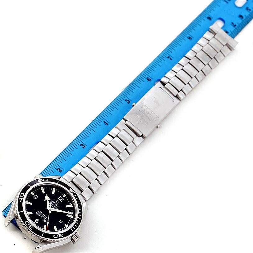 The image shows an Omega Planet Ocean 2200.50.00 Men
s Stainless Steel Black Dial 2200.50.00 Men
s Stainless Steel Black Dial watch laid flat next to a blue ruler, displaying the dial, case, and bracelet.