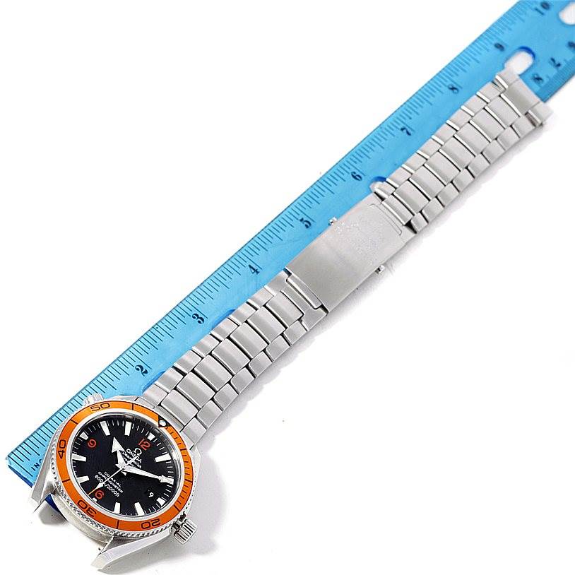 The image shows an Omega Planet Ocean 2209.50.00 Men
s Stainless Steel Black Dial 2209.50.00 Men
s Stainless Steel Black Dial watch, displaying its face, bezel, and full metal bracelet against a blue ruler.