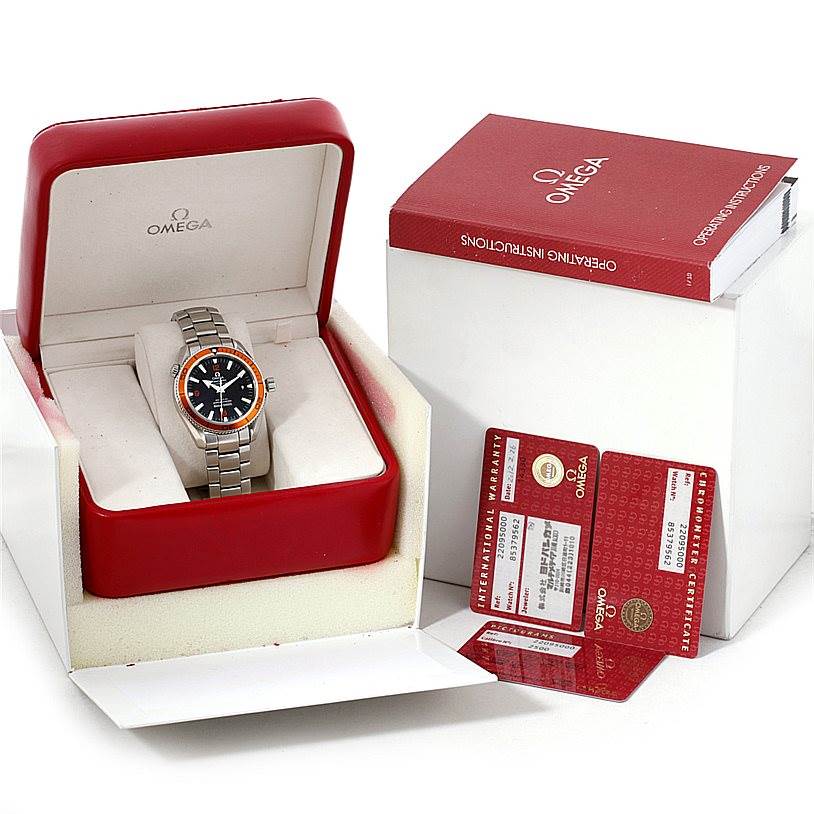 The Omega Planet Ocean 2209.50.00 Men
s Stainless Steel Black Dial 2209.50.00 Men
s Stainless Steel Black Dial watch is shown at an angle in its box, accompanied by warranty cards and an operating manual.