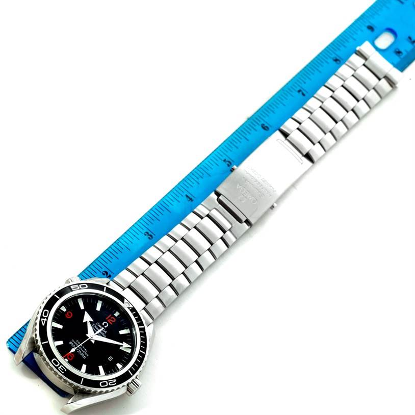 The Omega Planet Ocean 2200.51.00 Men
s Stainless Steel Black Dial 2200.51.00 Men
s Stainless Steel Black Dial watch is shown flat with its entire metal bracelet and clasp, next to a blue ruler for scale.