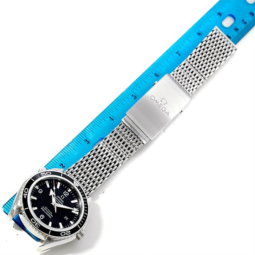 The Omega Planet Ocean 2200.50.00 Men's Stainless Steel Black Dial 2200.50.00 Men's Stainless Steel Black Dial watch is shown from a top-down angle, displaying its face and mesh bracelet next to a ruler for scale.