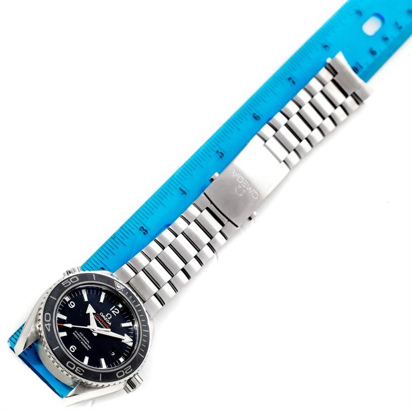 The Omega Planet Ocean 232.30.46.21.01.003 Men
s Stainless Steel Black Dial 232.30.46.21.01.003 Men
s Stainless Steel Black Dial watch is shown from a top-down angle, displaying the full face, bezel, and bracelet with a clasp over a blue ruler.