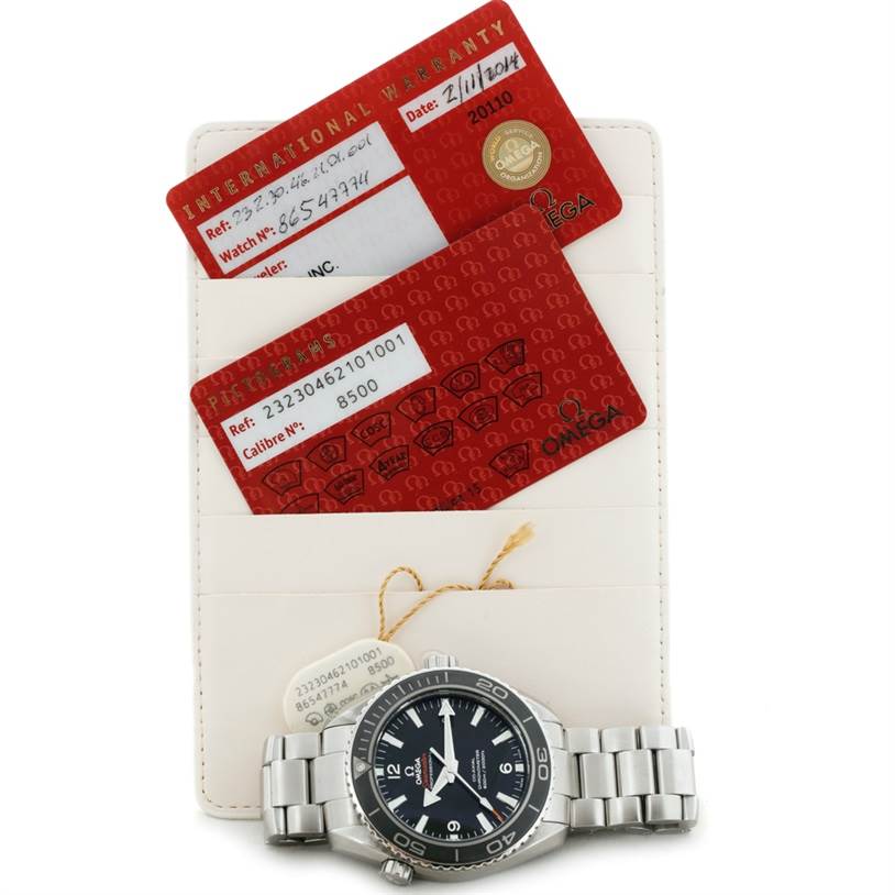 The image shows an Omega Planet Ocean 232.30.46.21.01.003 Men
s Stainless Steel Black Dial 232.30.46.21.01.003 Men
s Stainless Steel Black Dial watch laying flat, along with two warranty cards and a holder behind it.