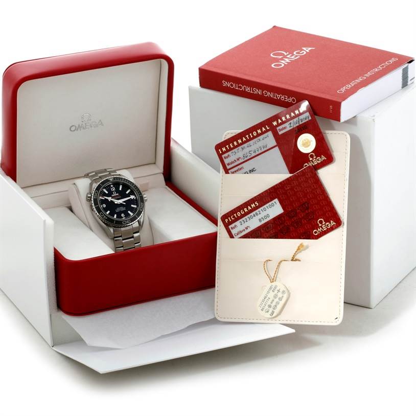 The image shows the Omega Planet Ocean 232.30.46.21.01.003 Men
s Stainless Steel Black Dial 232.30.46.21.01.003 Men
s Stainless Steel Black Dial watch in its box, accompanied by warranty cards, a manual, and an identification tag.