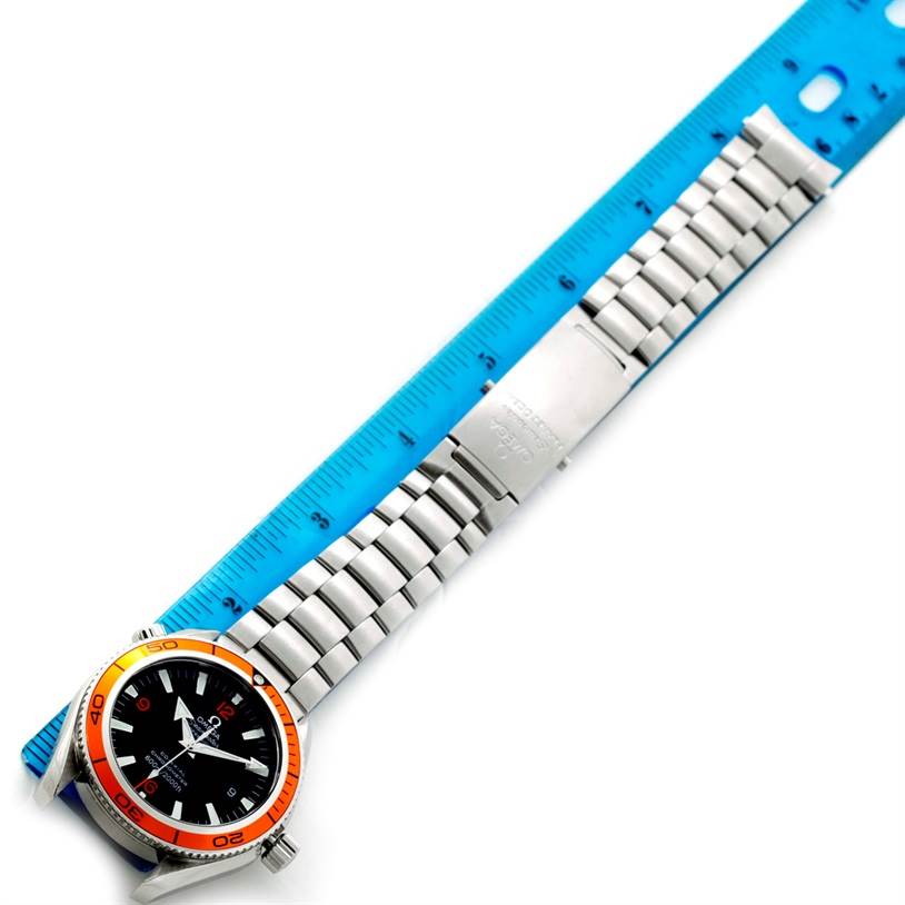 The image shows a top view of an Omega Planet Ocean 2209.50.00 Men
s Stainless Steel Black Dial 2209.50.00 Men
s Stainless Steel Black Dial watch with a stainless steel bracelet next to a blue ruler for scale.