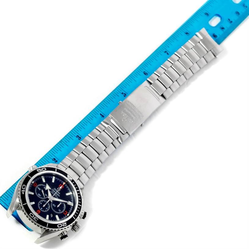 The image shows an Omega Planet Ocean 2210.51.00 Men's Stainless Steel Black Dial 2210.51.00 Men's Stainless Steel Black Dial watch laid flat, displaying its face and metal bracelet alongside a ruler for scale.