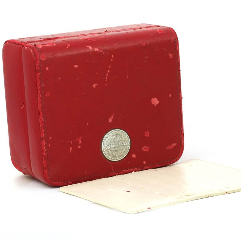 The image shows a red Omega watch case for the Aqua Terra model, viewed from the front with some wear marks and a white card beneath it.