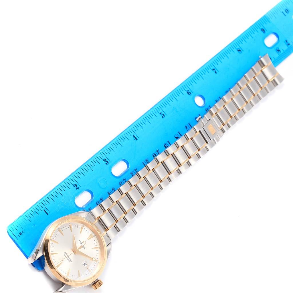 The image shows the Omega Aqua Terra 2317.30.00 Men
s Steel and Gold (two tone) Silver Dial 2317.30.00 Men
s Steel and Gold (two tone) Silver Dial watch laid flat with its bracelet extended next to a blue ruler for measurement.