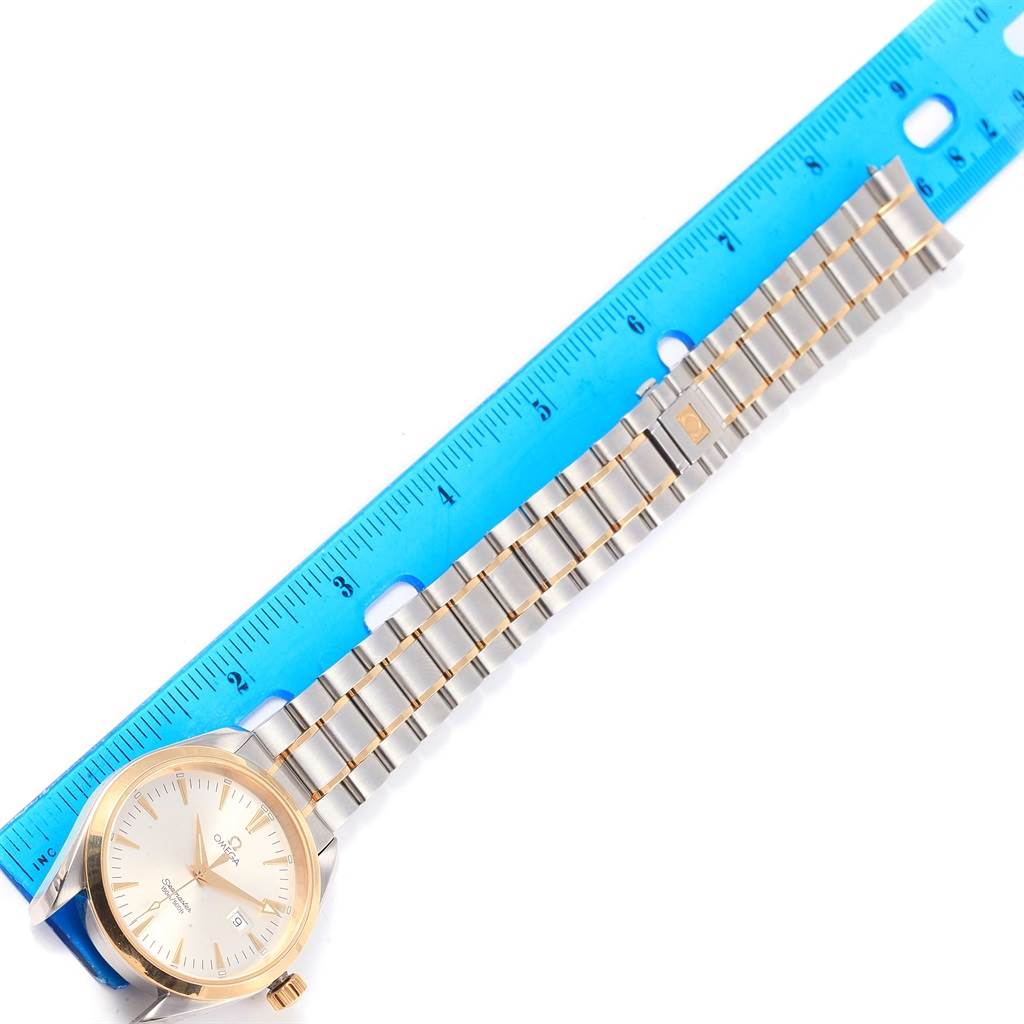 The image shows the front of an Omega Aqua Terra 2317.30.00 Men
s Steel and Gold (two tone) Silver Dial 2317.30.00 Men
s Steel and Gold (two tone) Silver Dial watch with its dial and full metal bracelet next to a blue ruler for scale.