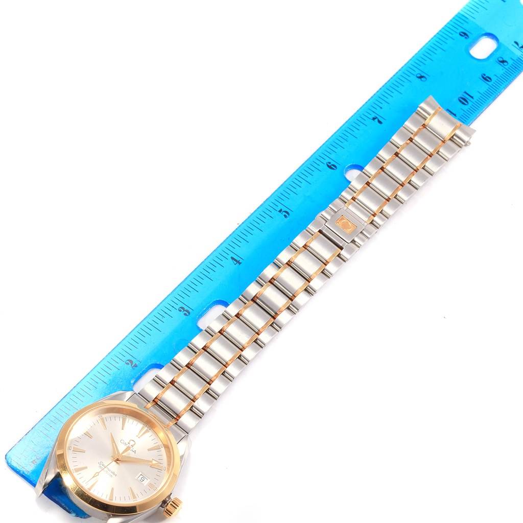 This image shows the Omega Aqua Terra 2318.30.00 Men
s Steel and Gold (two tone) Silver Dial 2318.30.00 Men
s Steel and Gold (two tone) Silver Dial watch face and metal bracelet links placed next to a blue ruler for size reference.