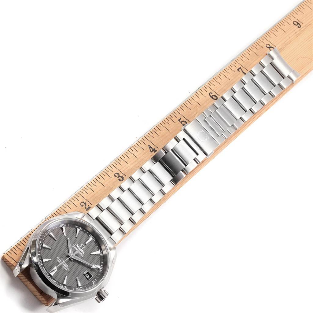 The Aqua Terra watch by Omega is shown flat with its face and metal bracelet laid next to a ruler for scale.