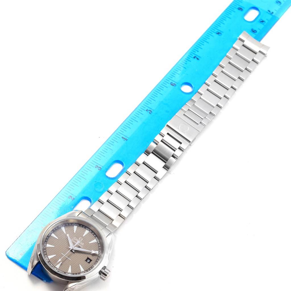 The image shows the Omega Aqua Terra 231.10.39.60.06.001 Men's Stainless Steel Grey Dial 231.10.39.60.06.001 Men's Stainless Steel Grey Dial watch and its metal bracelet beside a blue measuring ruler.